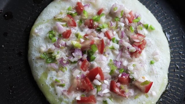 Indian chilla or uttapam prepared on black pan in kitchen