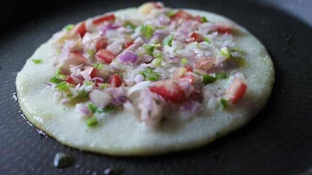 Indian chilla or uttapam prepared on black pan in kitchen