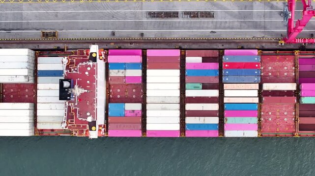 A massive container ship arrives at a busy cargo port, unloading colorful shipping containers. Workers efficiently move goods to ensure smooth operations in global trade and logistics.