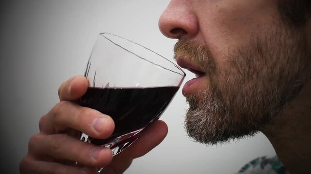 Close-up of a man's profile tasting red wine in a glass
