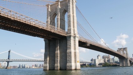 Fototapeta premium Brooklyn Bridge and Manhattan Bridge from Downtown, New York City, United States. Esplanade pier park in NYC USA. American architecture, famous tourist landmark. Waterfront urban promenade.