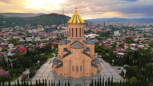 aerial view of the Holy Trinity Cathedral of Tbilisi (Sameba) at sunset. Dramatic front perspective of the monumental Georgian Orthodox church with the city skyline in the background