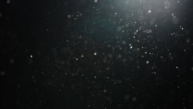 Slow motion real dust particles floating mid air over dark background