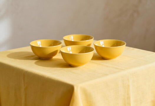 Set of four yellow ceramic bowls on tablecloth with dishware tableware tablecloth arrangement