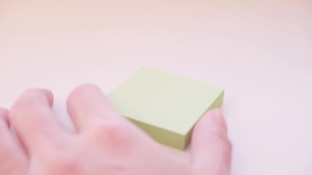 A hand writes the phrase "I love you" with a pen on a block of yellow stickers. Video footage of the process of writing a confession.
