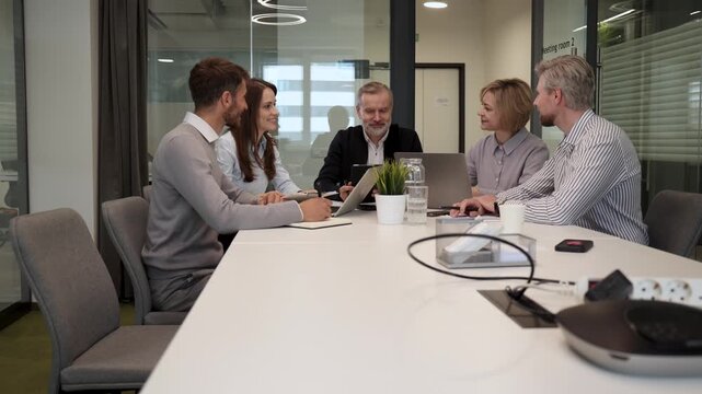 Successful businesspeople working in a coworking space working with laptop discussing strategy and business plan in modern office.