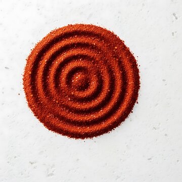 Red spice powder formed into a circular pattern with concentric rings. aleppo pepper flakes