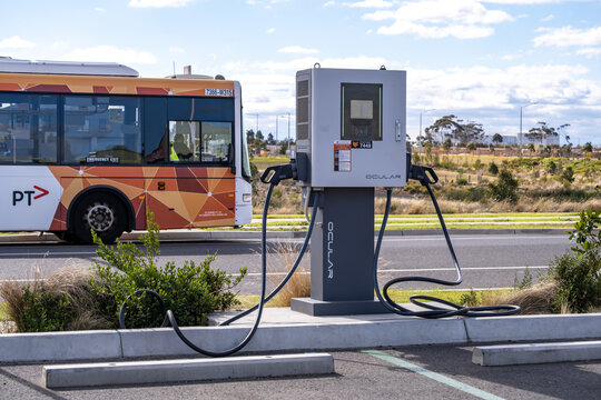 An Ocular brand electric vehicle charging station in a suburban car park in Truganina, Melbourne,  Australia, with a Public Transport Victoria (PTV) bus in the back