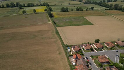Fototapeta premium Aerial Fields and Homes: An expansive aerial perspective captures a harmonious blend of rural agriculture and residential community life. This scene. Caleppio, Lombardy, Italy