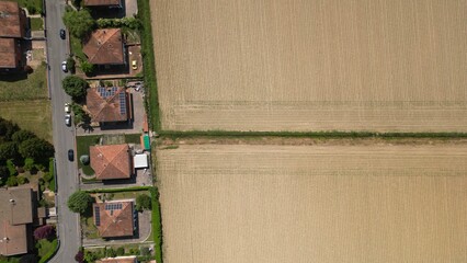 Aerial View of Residential Area and Farm Field: An eye-level aerial shot presents a captivating composition: on one side, a tranquil residential area of houses, and on the other, a vast field. © Andrew