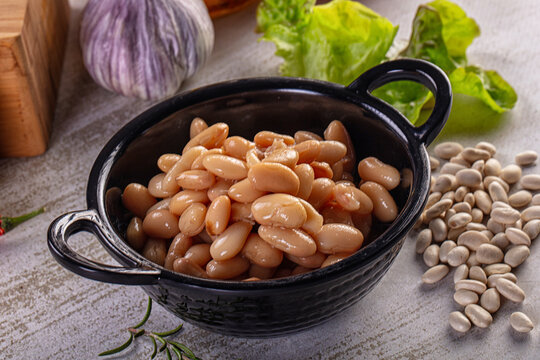 Rustic still life of cooked cannellini beans with fresh vegetables and spices