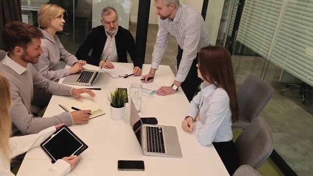 Successful businesspeople working in a coworking space working with laptop discussing strategy and business plan in modern office.