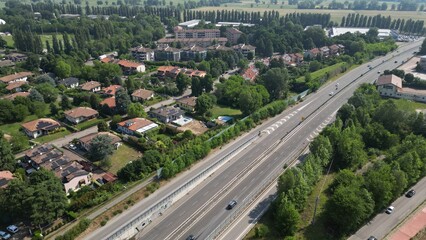 Obraz premium A high-angle perspective showcasing a vast network of roads winding through a town, surrounded by verdant trees and lush greenery. Pantigliate, Milan, Italy