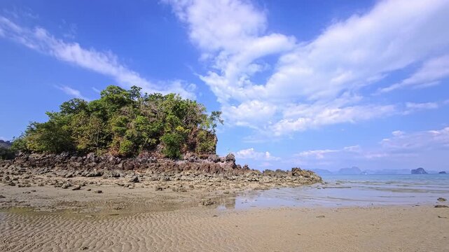 Rocky tropical islet surrounded by exposed sand and shallow water