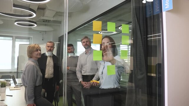 Creative group or business people planning innovation with sticky notes on glass wall.