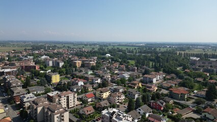 Fototapeta premium Aerial Cityscape Under Clear Skies: A vibrant scene, showcasing a city's architectural diversity under a bright, cloudless sky, promising endless possibilities. Pantigliate, Milan, Italy