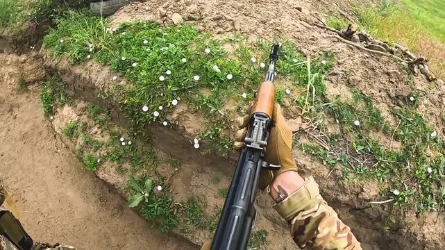 Two infantrymen walk forward along the trench of the trench, with their machine guns cocked, ready to shoot back. Real hostilities, defense and offensive positions. Russo-Ukrainian war.