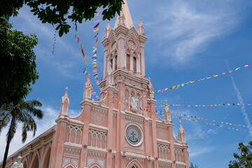 Fototapeta premium Pink Cathedral in Da Nang, Vietnam under blue sky with colorful festival flags