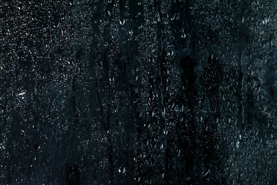 Transparent water droplets glass window overlay black background photo.