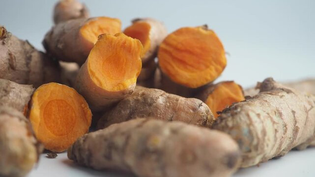 Fresh turmeric roots and sliced pieces on white background