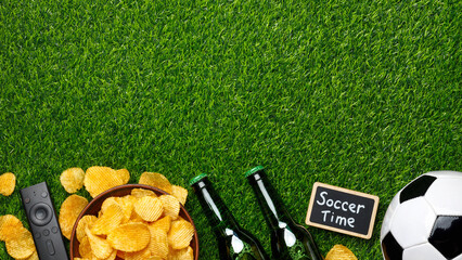 Naklejka premium Green beer bottles, potato chips, a classic soccer ball, TV remote and a small chalkboard sign 