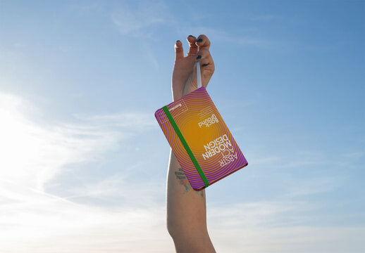 Detailed Mockup of a Blank Notebook Held in the Sky
