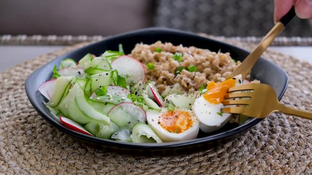 Cutting Soft Boiled Egg in Healthy Breakfast Bowl Close Up