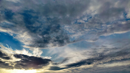 Obraz premium Dramatic storm clouds and textured sky illuminated by soft sunset light with deep blue tones. Ideal to illustrate weather, emotion, inspiration, and cinematic website backgrounds.