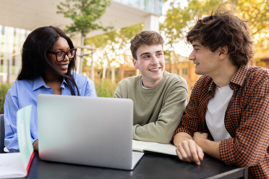 University students collaborating on project outdoors with laptop