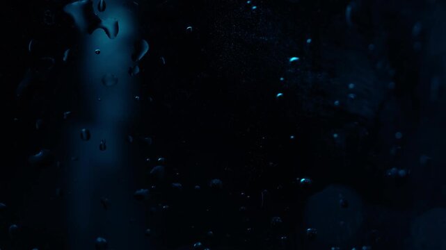 Carbonated water is poured into a transparent glass, macro view of bubbles in the glass on a black background