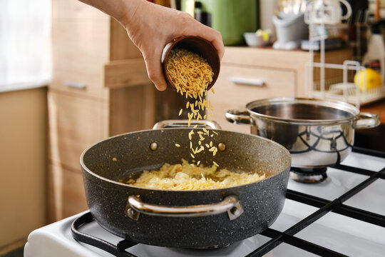 Add pasta orzo into a frying pot with chopped onion