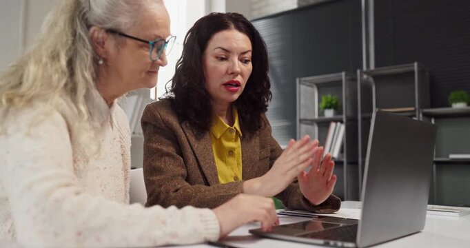Senior woman meeting advisor retirement planning finance investment. Advisor gestures and explains options on laptop, guiding client through risk. Clear concept of pension consultant.