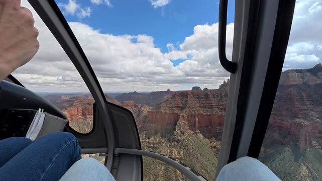 Pov view from inside a helicopter flying above the majestic grand canyon, with a passenger taking pictures with a smartphone of the breathtaking red rock formations and canyons in arizona