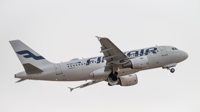 Finnair Airbus A319-112 taking off with landing gear retracting. Detailed view of the fuselage, CFM56 engines, and wings against a clear sky during departure. Illustrative editorial.