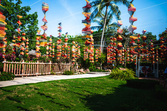 Wide view of a lawn and path decorated with many colorful wind spinners in a tropical park.