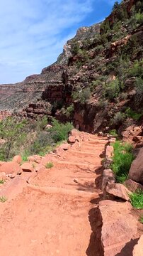 Point of view walking down the steep, dusty switchbacks of the bright angel trail, revealing the immense and majestic landscape of the grand canyon national park in arizona on a sunny day