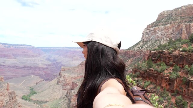 Happy smiling woman hiker filming a video selfie during a trip, enjoying the stunning panoramic view of the grand canyon national park from the bright angel trailhead in arizona