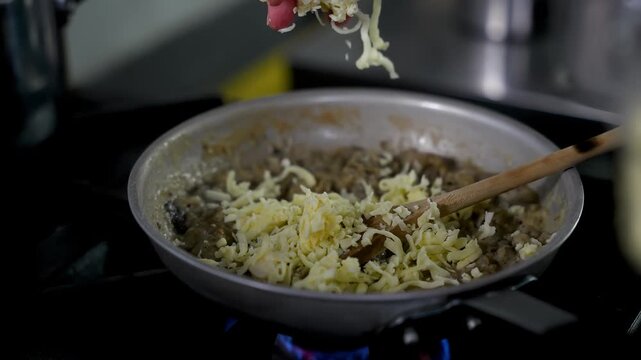 Chef Adding Cheese to Traditional Turkish H&uuml;nkar Beğendi in Frying Pan