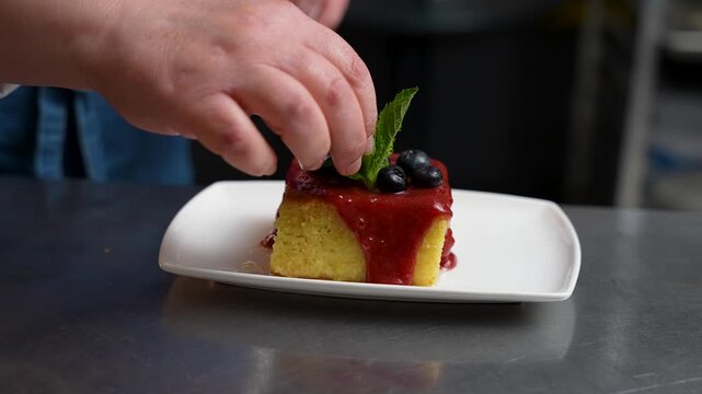 Mint Garnish Being Added to Turkish Revani Dessert with Plum Sauce