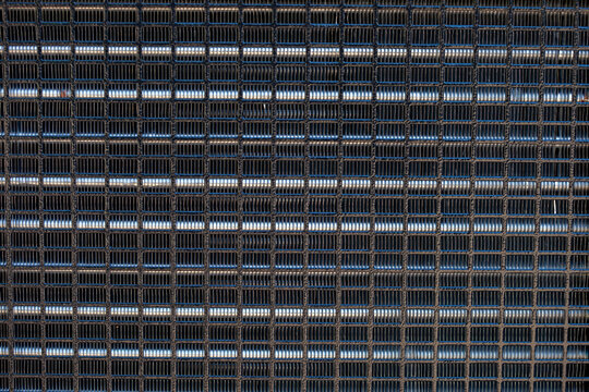 industrial metal grid with precise square cells and horizontal shiny metal bars. Technical texture of a protective grille, ventilation screen, or heat exchanger component used in machinery, equipment,
