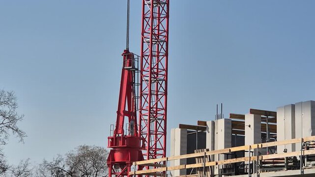 Positioning a steel tower top section with a crane to the base structure in the initial phase of assembly before lifting.
