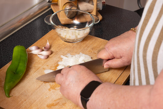 Hands chopping onion on cutting board for meal prep