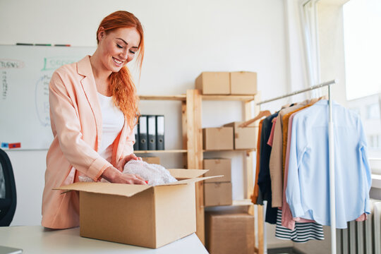 Young woman packing clothing order in small business office