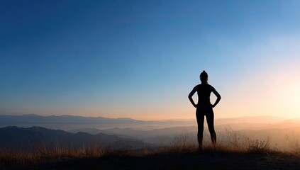 Fototapeta premium Silhouette of a woman standing on a mountaintop at sunrise