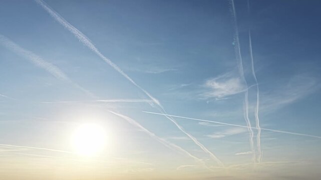 Bright morning sky with crossing airplane vapor trails