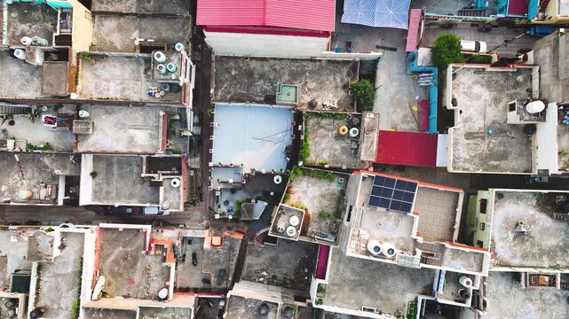 Bird's-eye view tracking over clustered urban houses and water tanks.