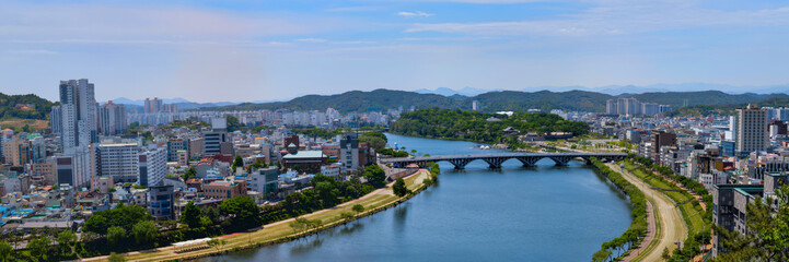 Obraz premium Jinju City panoramic skyline with modern buildings, Namgang River, and landmark Cheonsugyo Bridge in Gyeongsangnam‑do, South Korea