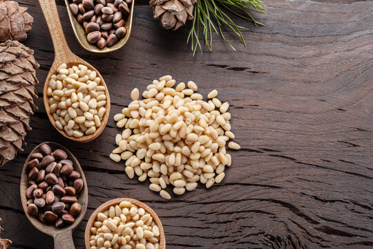 Pine nuts or cedar nuts with cedar cone on a wooden background.