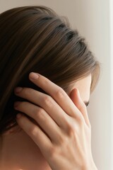 Fototapeta premium Woman touches hairline showing thinning hair and scalp. Gentle hand motion suggests concern or self examination for hair loss treatment and scalp care.