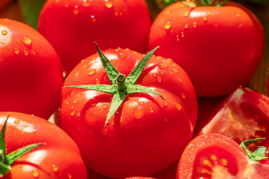 Fresh red tomatoes and slices with green leaves